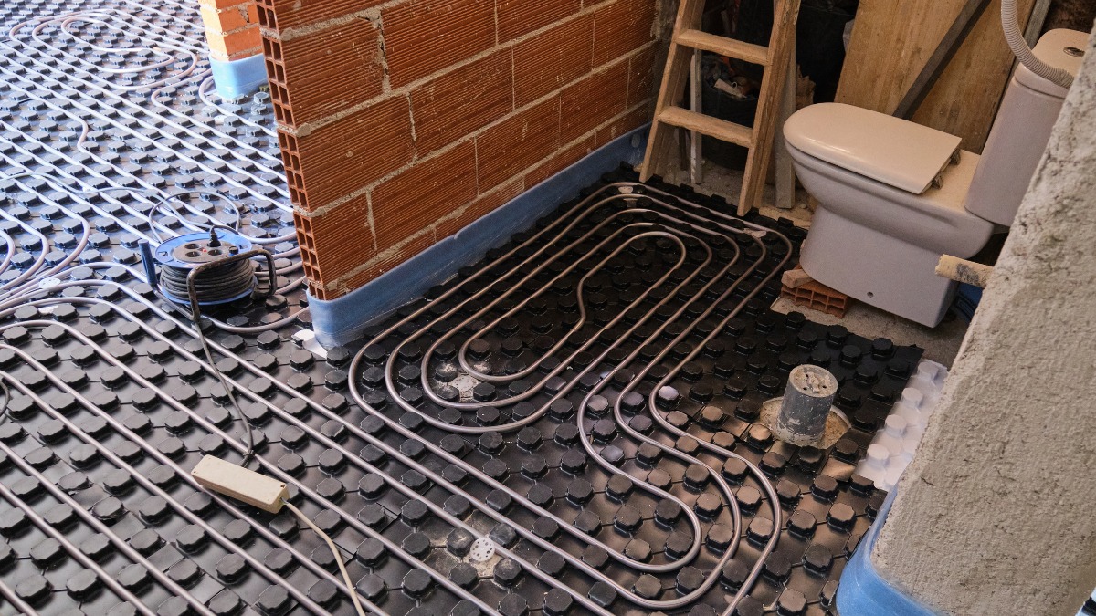 Underfloor heating pipes laid out on black castellated panels in a bathroom