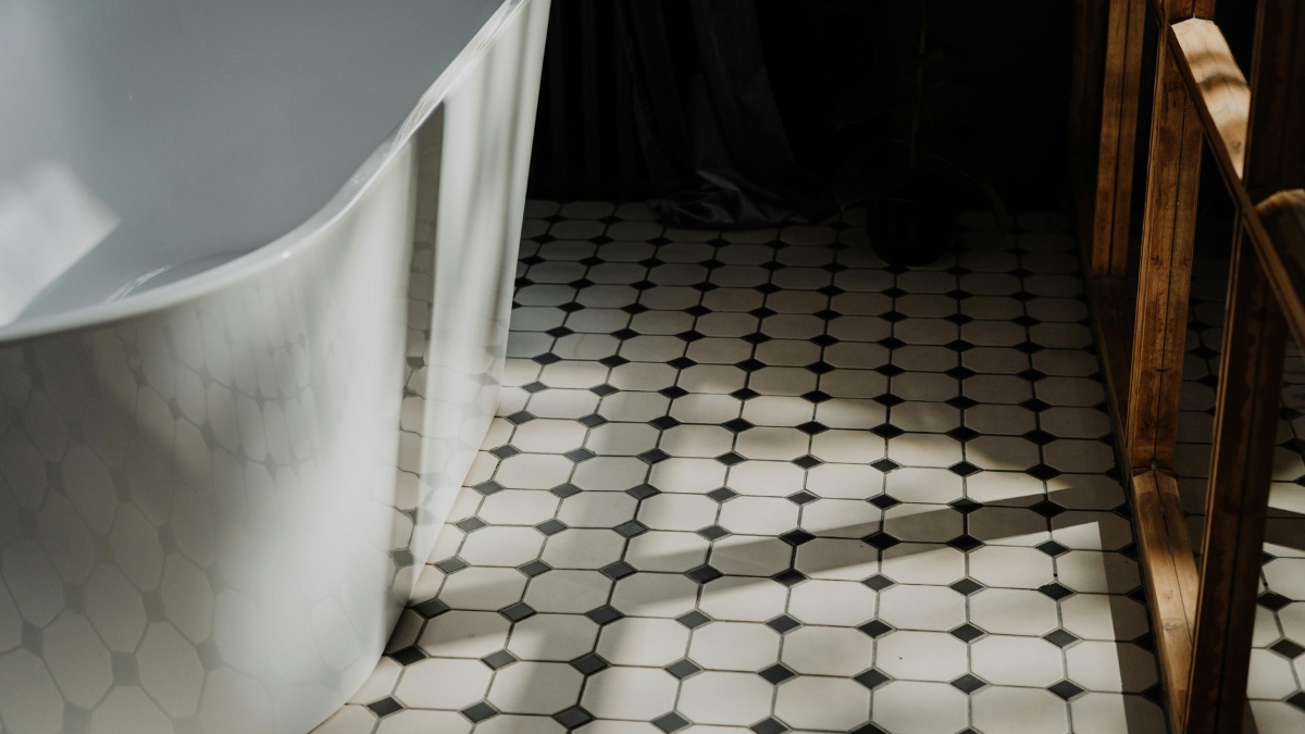 A white freestanding bathtub next to a classic black and white octagon tile floor